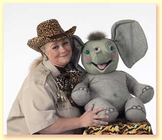 Photo of Margaret Clauder as Masai Maggie, posing with Sneezy The Elephant, a puppet in the show.